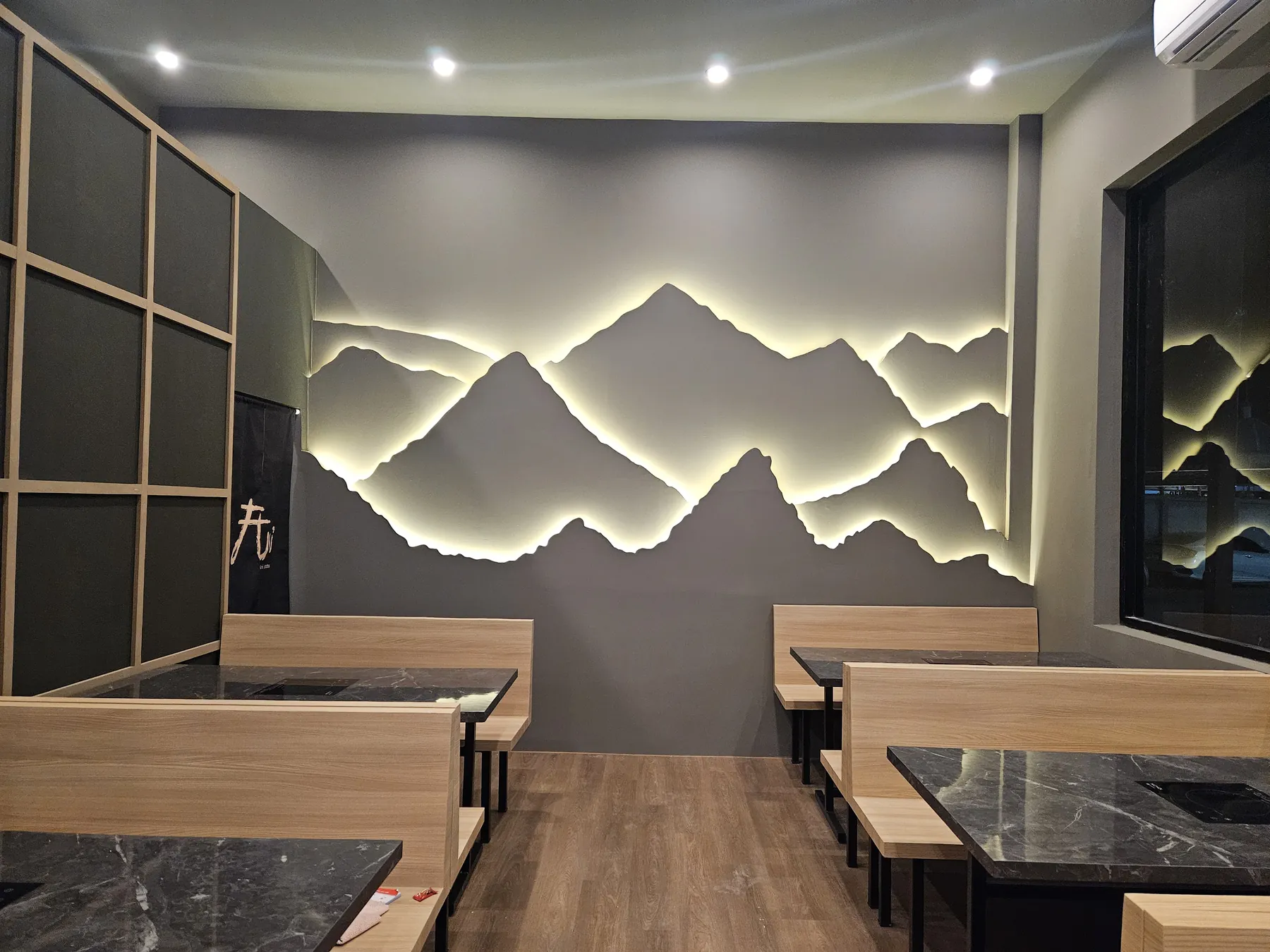 โซนผนังลายภูเขายามค่ำ พร้อมโต๊ะหินและเก้าอี้บูธไม้ ร้าน Ani Shabu