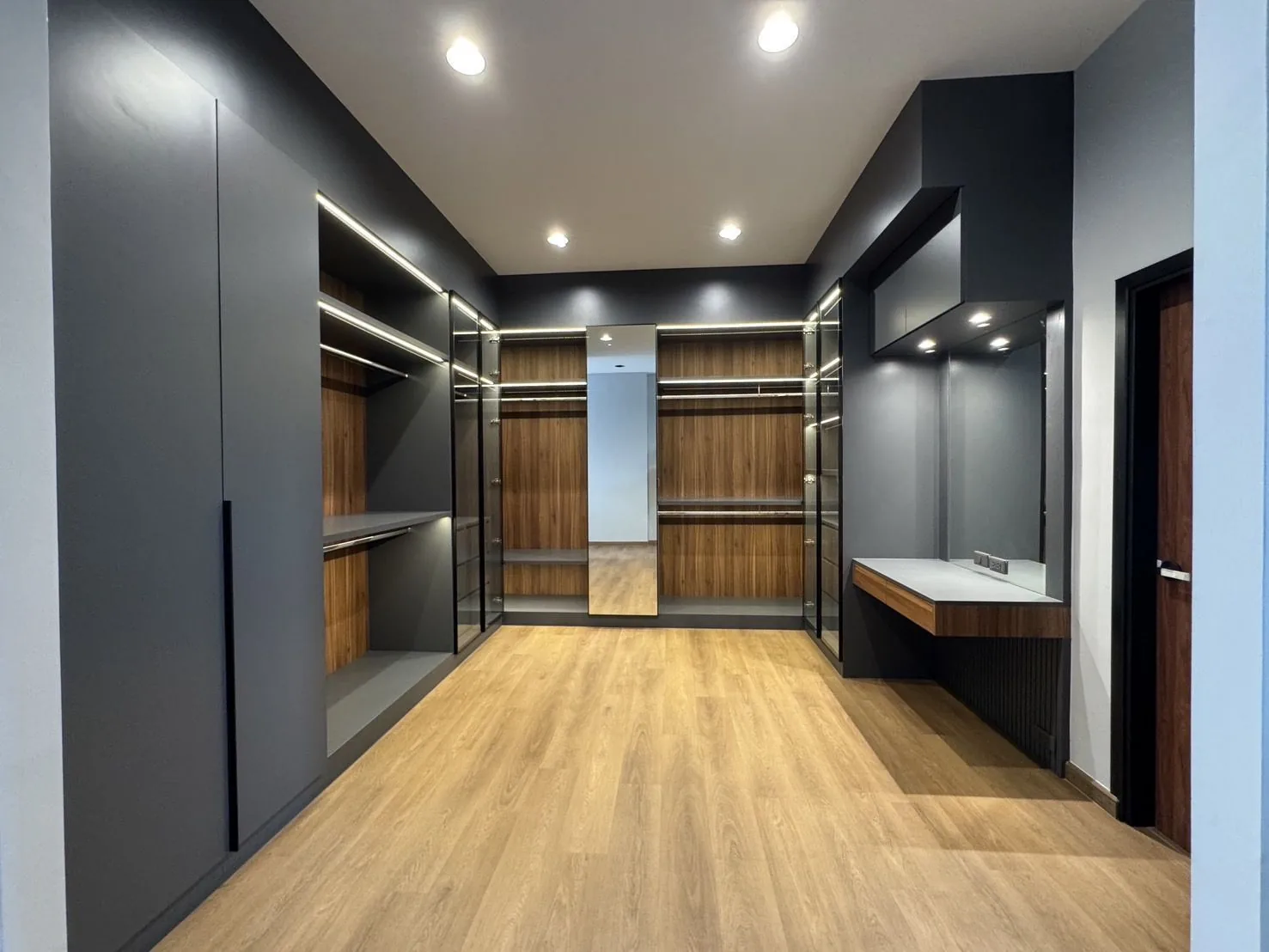 บ้านพักอาศัย สมุทรสงคราม — ห้องแต่งตัว walk-in closet บิวท์อิน โทนเทาเข้มและไม้ พร้อมไฟซ่อนในตู้